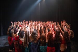 danseuses sur scène bras et mains en l'air vers le centre ensemble