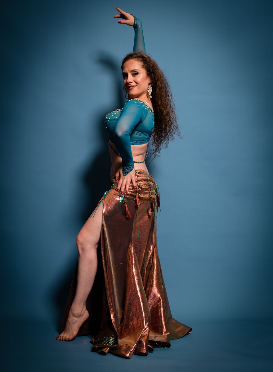 Danseuse orientale en costume bleu et cuivré, bras levé