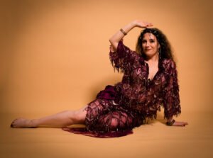 danseuse orientale en costume baladi, assise au sol en studio photo