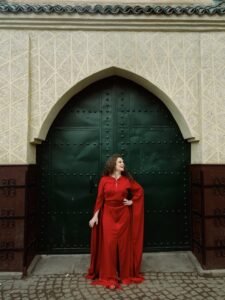 danseuse qui pose devant une grande porte à Marrakech